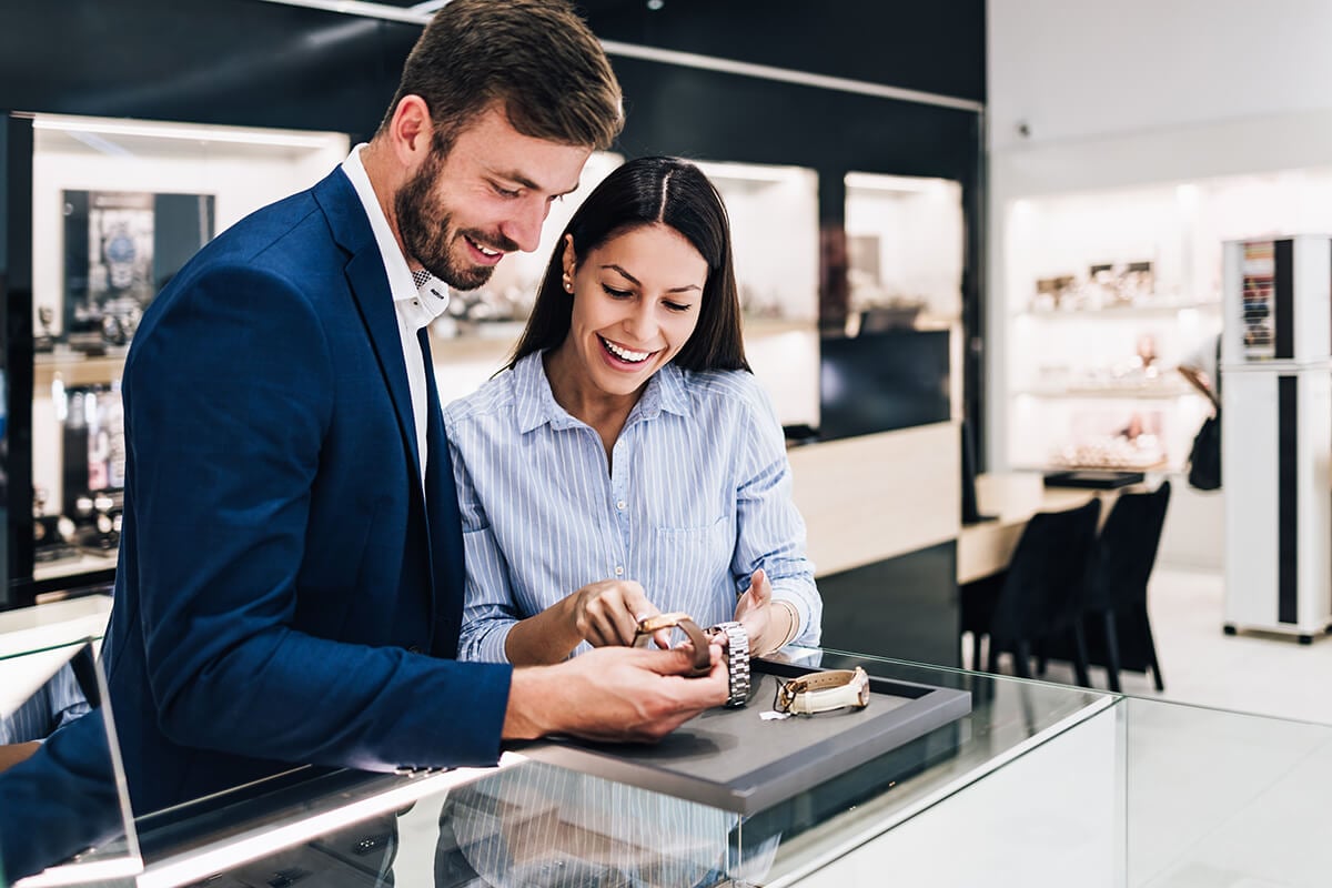 A man and woman looking at a watch in a store