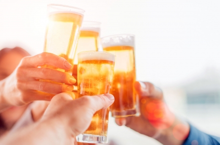 A group of people raising a toast with their beers in hand