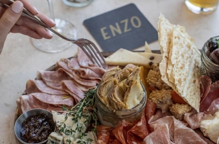 charcuterie board at ENZO Steakhouse & Bar with cocktail and beer