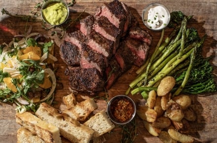 ENZO Steakhouse & Bar menu items of cut stak, broccoline, fingerling potatoes and crostinis.